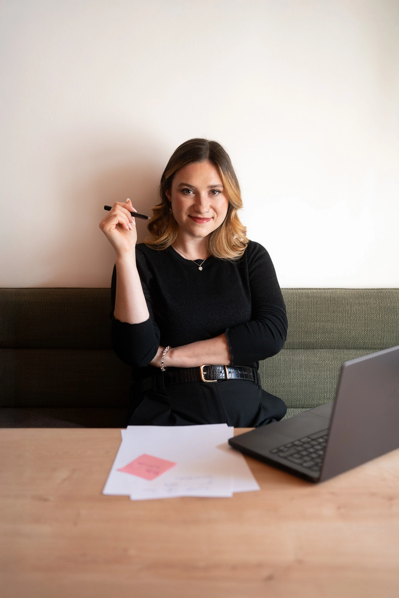 Lucia Reinsprecht, Kommunikationsspezialistin aus Oberösterreich, sitzt an einem Schreibtisch mit Notizblock und Laptop. Sie hält einen Stift in der Hand und blickt konzentriert nach vorne. Das Bild symbolisiert professionelle Beratung in Marketing und Öffentlichkeitsarbeit.